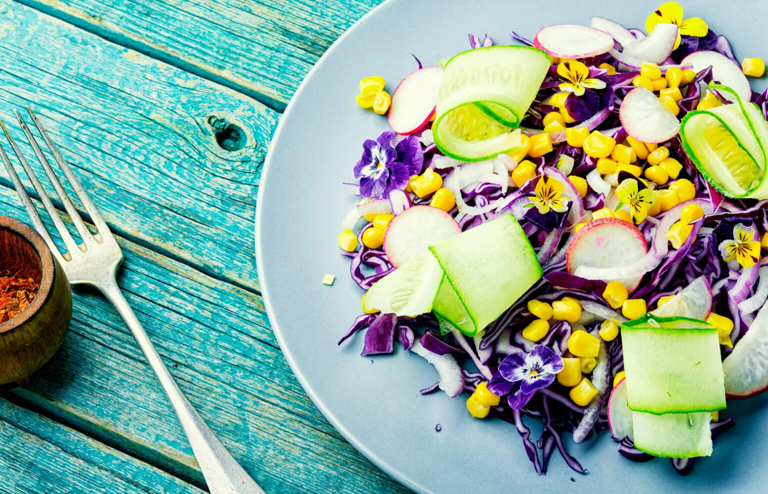 A plate of healthy salad containing corn, edible flowers and more.