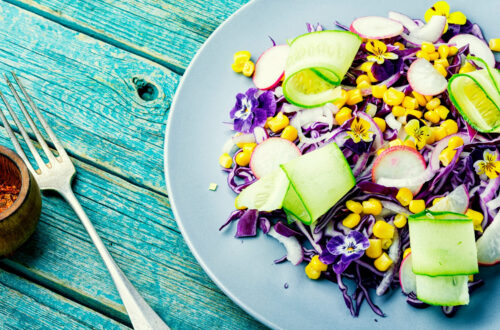 A plate of healthy salad containing corn, edible flowers and more.