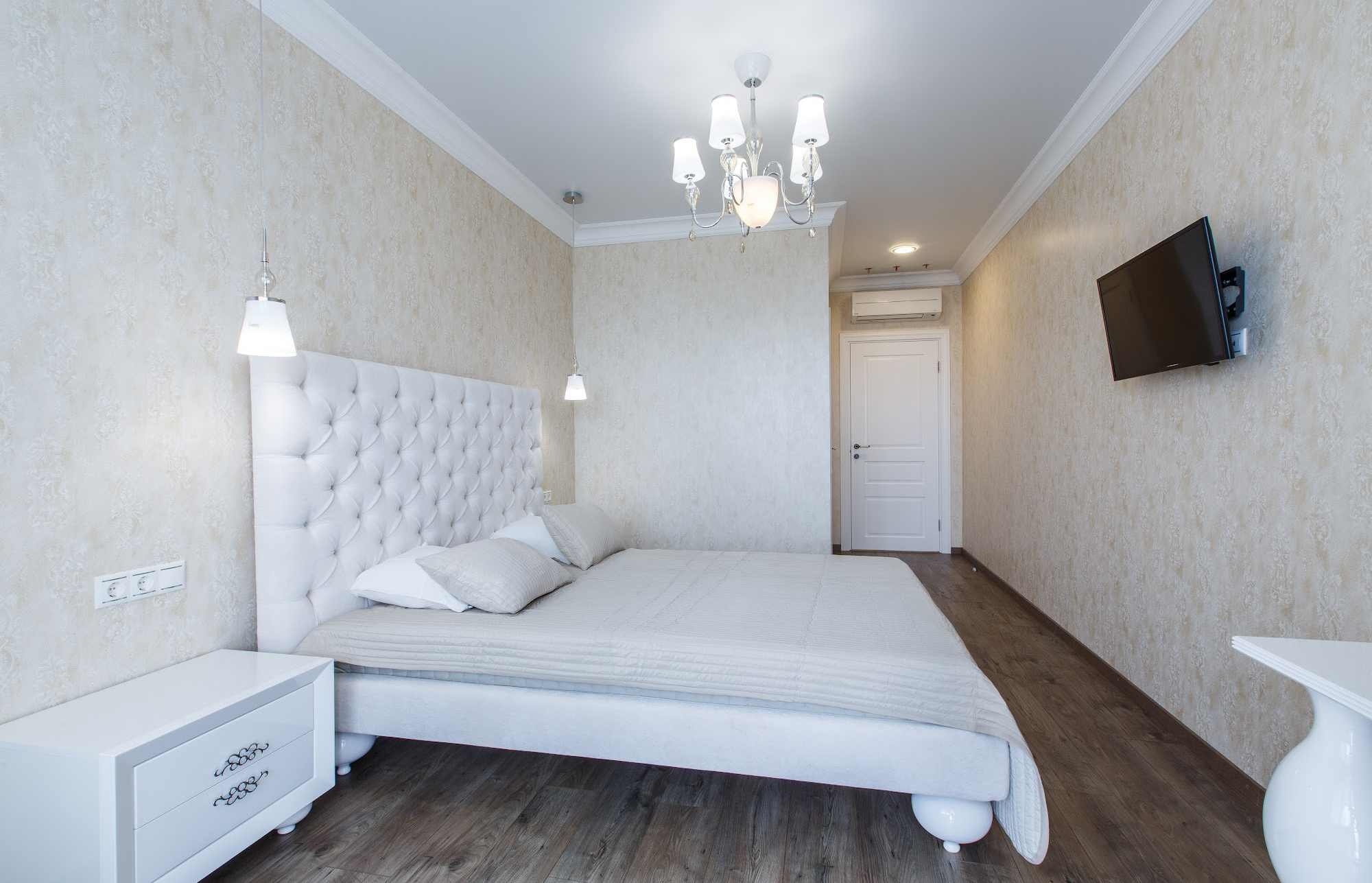 A hotel room with a white bed in the middle of the room.