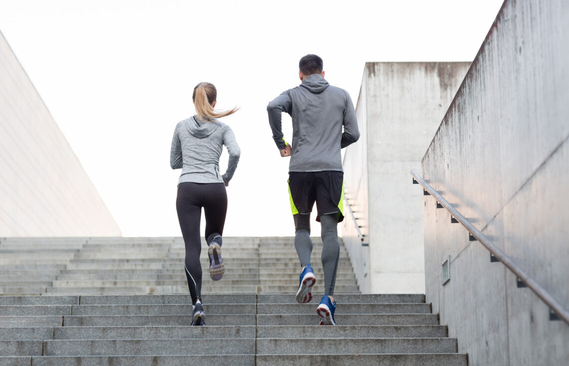 A man and a woman running up the stairs while exercising.