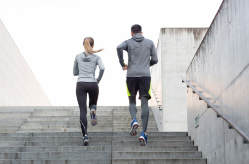 A man and a woman running up the stairs while exercising.