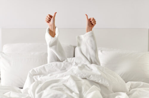 Women in a white bed giving a double thumbs up.