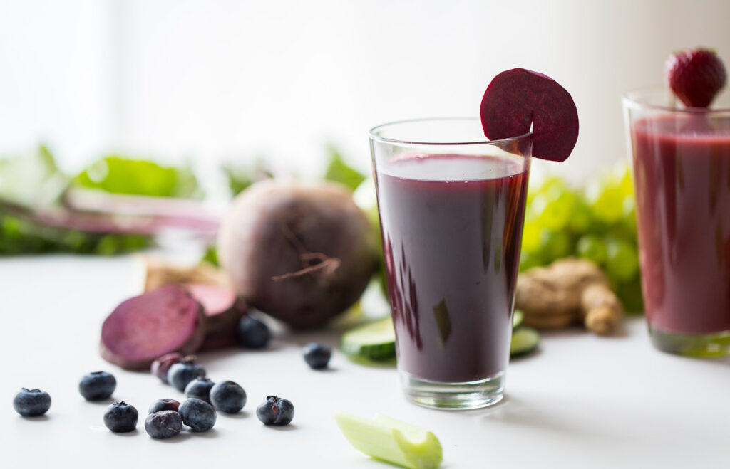 Beet juice in 2 glasses on a white surface.