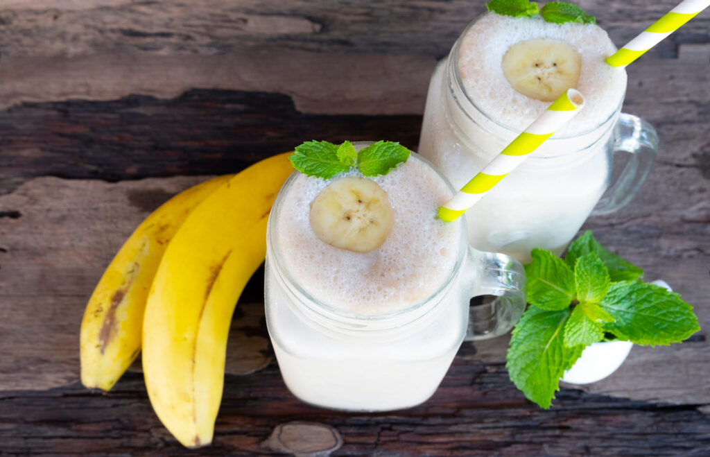 Maca vanilla smoothie in 2 mason jar mugs on a wooden table.