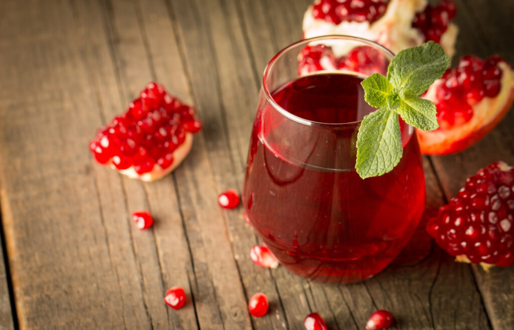 Pomegranate juice in a glass on a wooden surface.