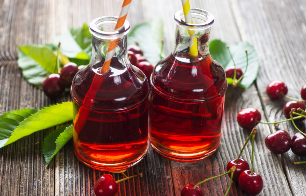 Tart cherry juice in 2 jars on a wooden table