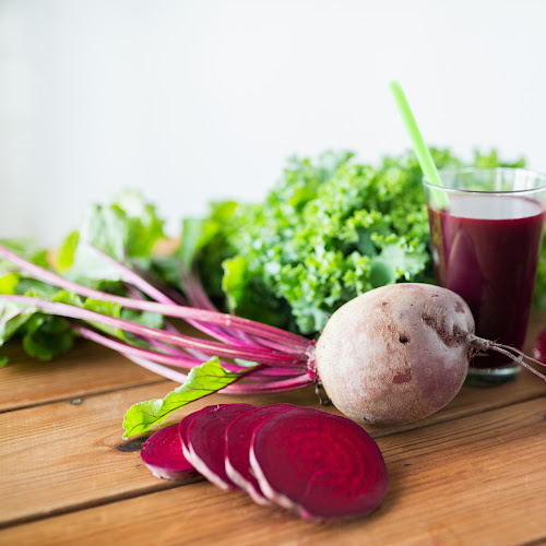 Beet root and beet root juice in a glass on a wooden table.