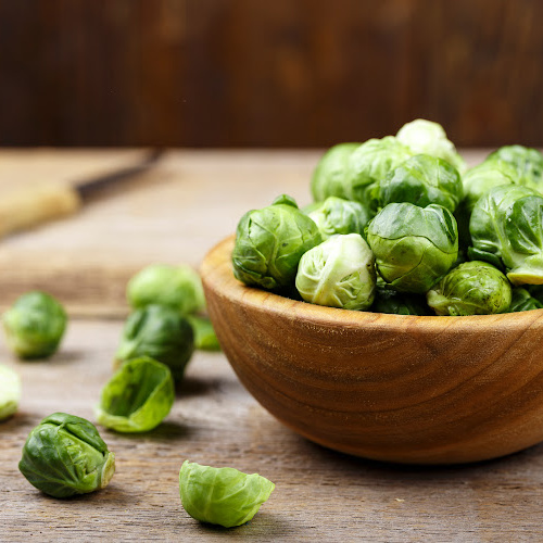 Brussels sprouts in a wooden bowl on a wooden table.
