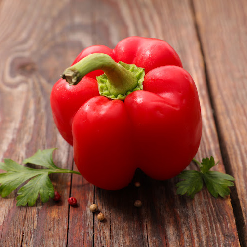 red bell pepper and cilantro on a wooden surface